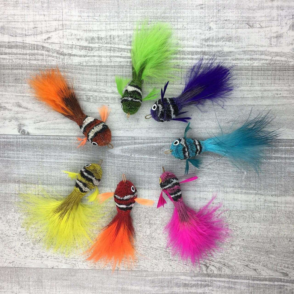 These are an assortment of Pretty Fly Clownfish Teaser Wand Cat Toy Replacement Lures by Catboutique. They are orange, burnt orange-red, green, purple, light blue, yellow, hot pink, and neon green. They are made out of deer hair and have feather tails. Each lure is colored with a dye that isn't harmful to cats. This lure is meant to engage at the cat's hunting instincts like prowling, pawing, and pouncing. 