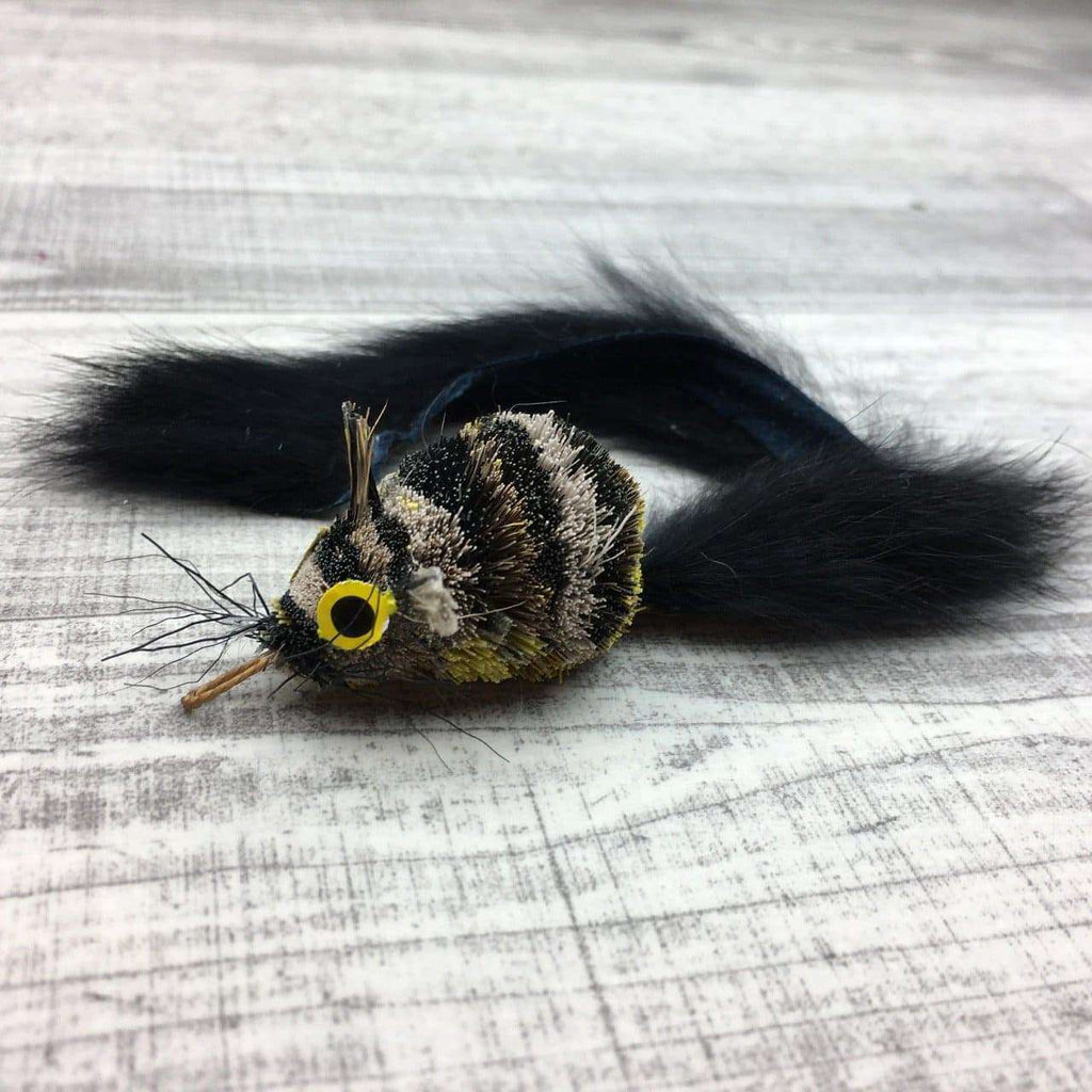This is a Pretty Fly Mouse Teaser Wand Cat Toy Replacement Lure by Catboutique. The lure is made of real deer fur. The lure has a cotter clip ring where the mouth should be. It has a long bushy tail too. The lure is colored with a dye that isn't harmful to cats. This mouse has two huge eye that stand apart from the body. The mouse is tan and black striped with a yellow underbelly. This lure is meant to engage at the cat's hunting instincts like prowling, pawing, and pouncing. 