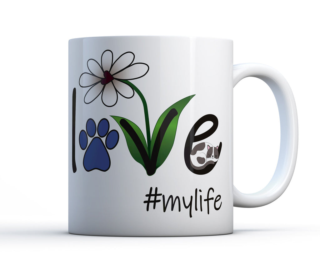 A white ceramic coffee mug with the words Love #mylife, a flower and a sleeping cat or kitten. 
