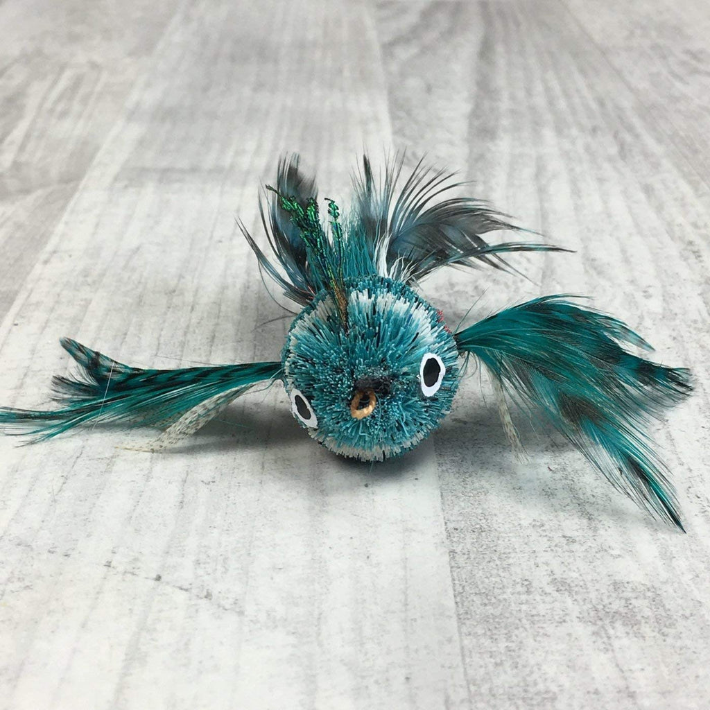 This is a Pretty Fly Bird Teaser Wand Cat Toy Replacement Lure by Catboutique. The bird is made from real deer hair and it gives a bristly hair appearance. It has bird feather for wings and a tail. There is a cotter ring clip where the beak should be. The bird is mostly turquoise with a white strip near the eyes. This lure is meant to engage at the cat's hunting instincts like prowling, pawing, and pouncing. The lure works best with a teaser wand cat toy.